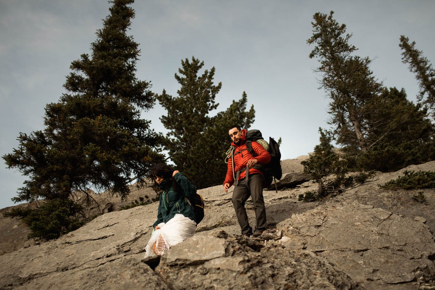 bride and groom climbing down mountain